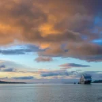 An image of a cruise liner approaching Warrenpoint around sunset time with calm water and the mourne mountains flanking each side