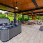 An image of the relaxation area at Rosie's Cottage, the image shows the hot tub, bench, grill, couches, and outdoor bar area.