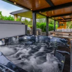 Closeup of the Hot Tub at Rosie's Cottage, with the grill, bench, and couches in the background.