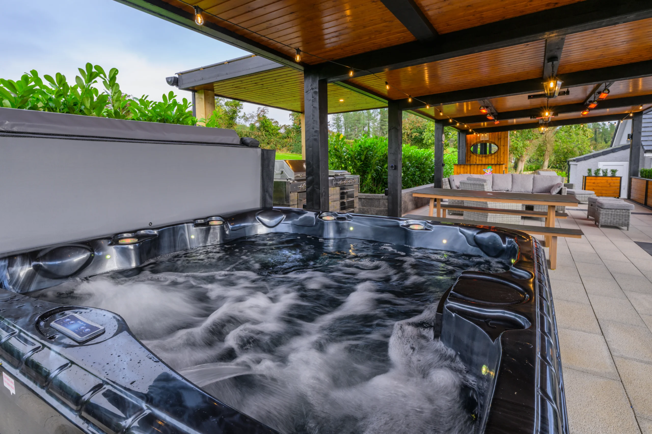 Closeup of the Hot Tub at Rosie's Cottage, with the grill, bench, and couches in the background.
