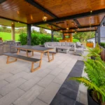 An image of the outdoor relaxation area at Rosie's Cottage, showcasing the wooden bench table, grill area, and couches.