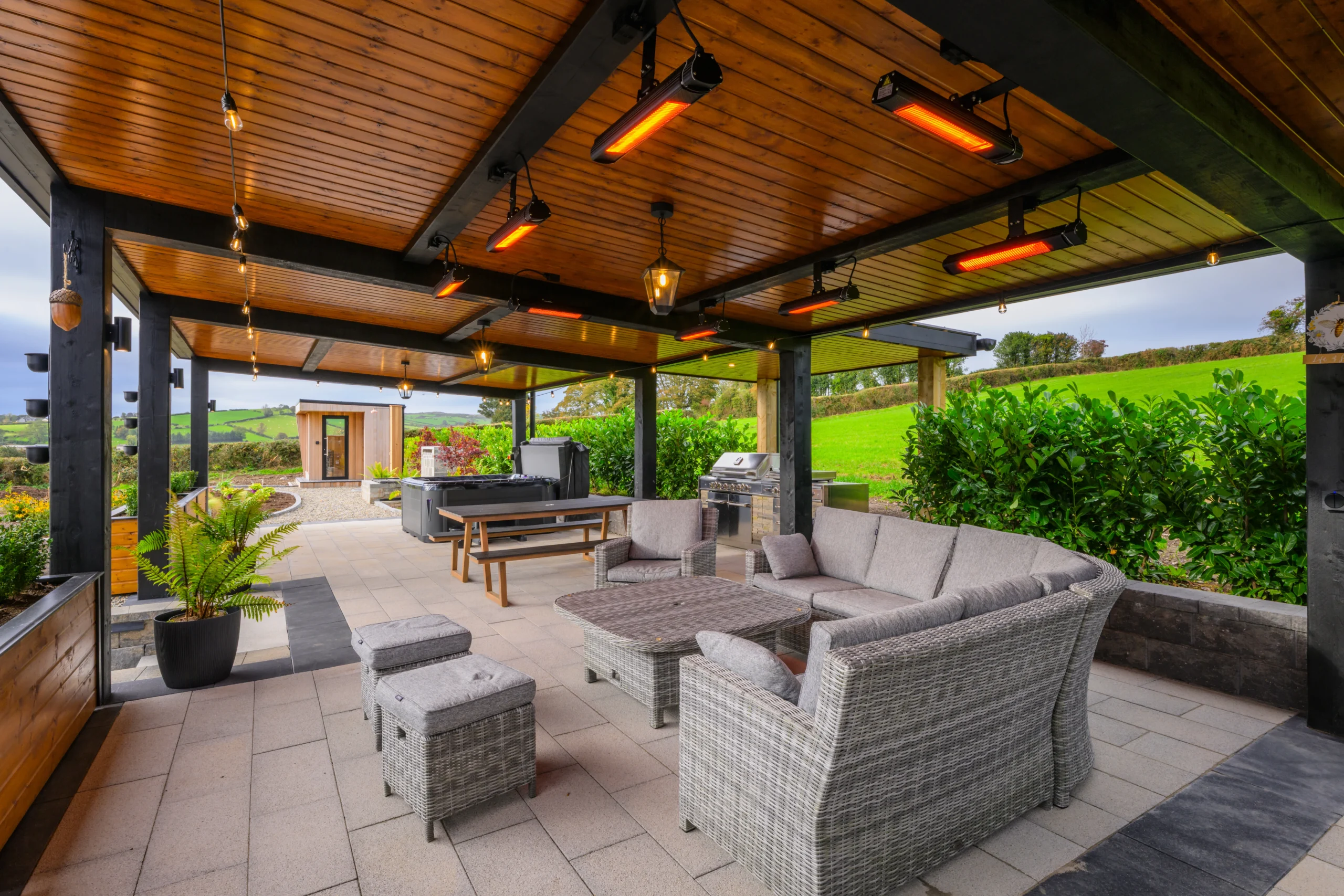 An image of the Outdoor relaxation and recreation area showcasing the hot tub, grill, bench, and couches.