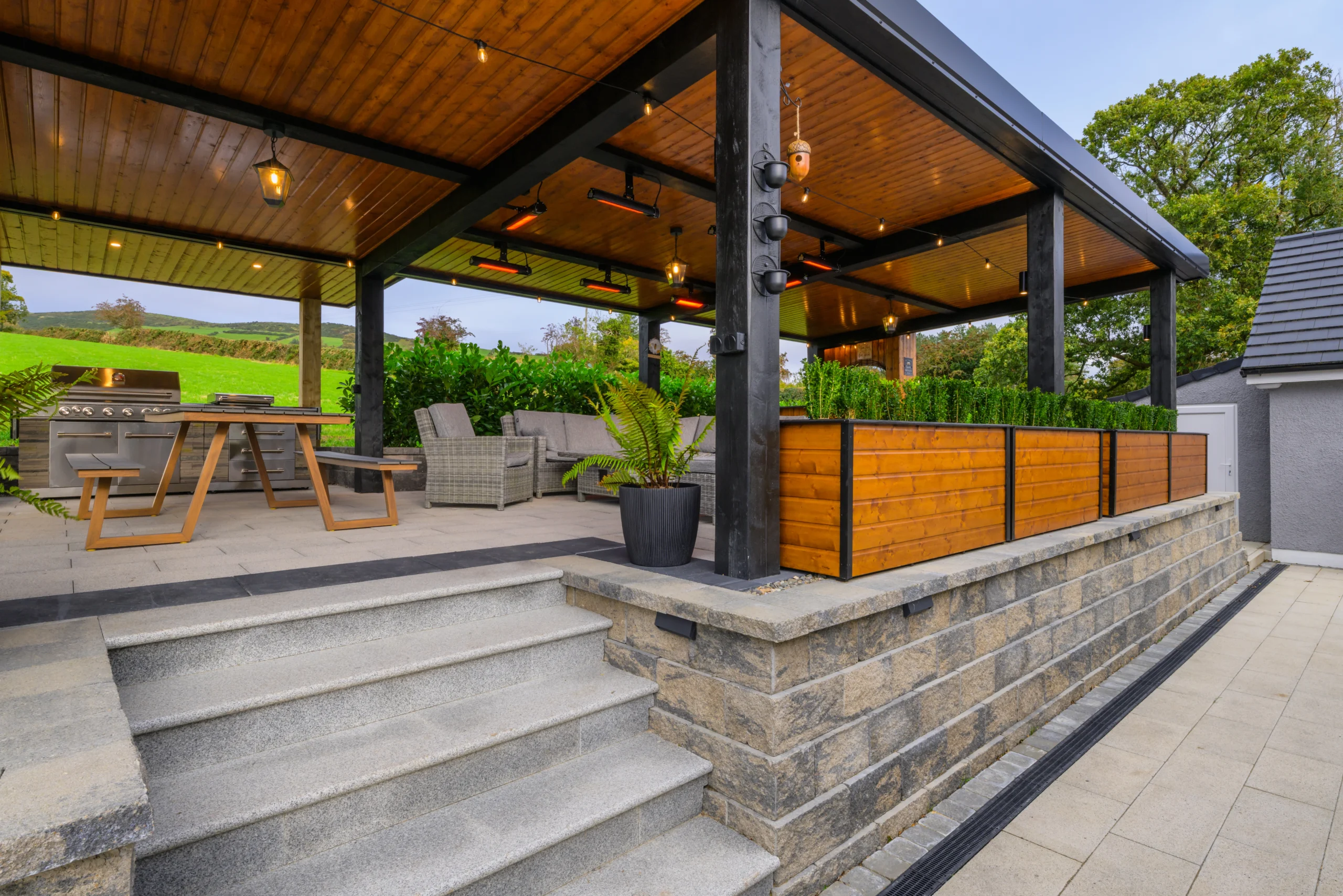 View of the Relaxation area from the bottom of the stairs. Showcasing the table and grill with the couches just in view