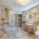 Image of Lily's Pink house bathroom showcasing the walk-in shower, with frosted glass privacy screen, toilet, and floating sink area.
