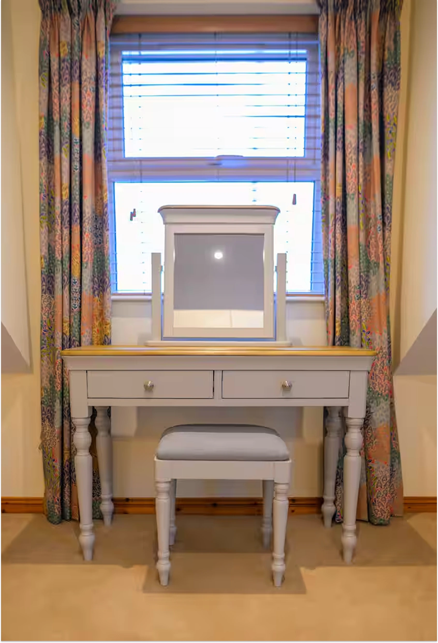 Vanity in a bedroom at Lily's Pink house with a mirror, drawers, and stool