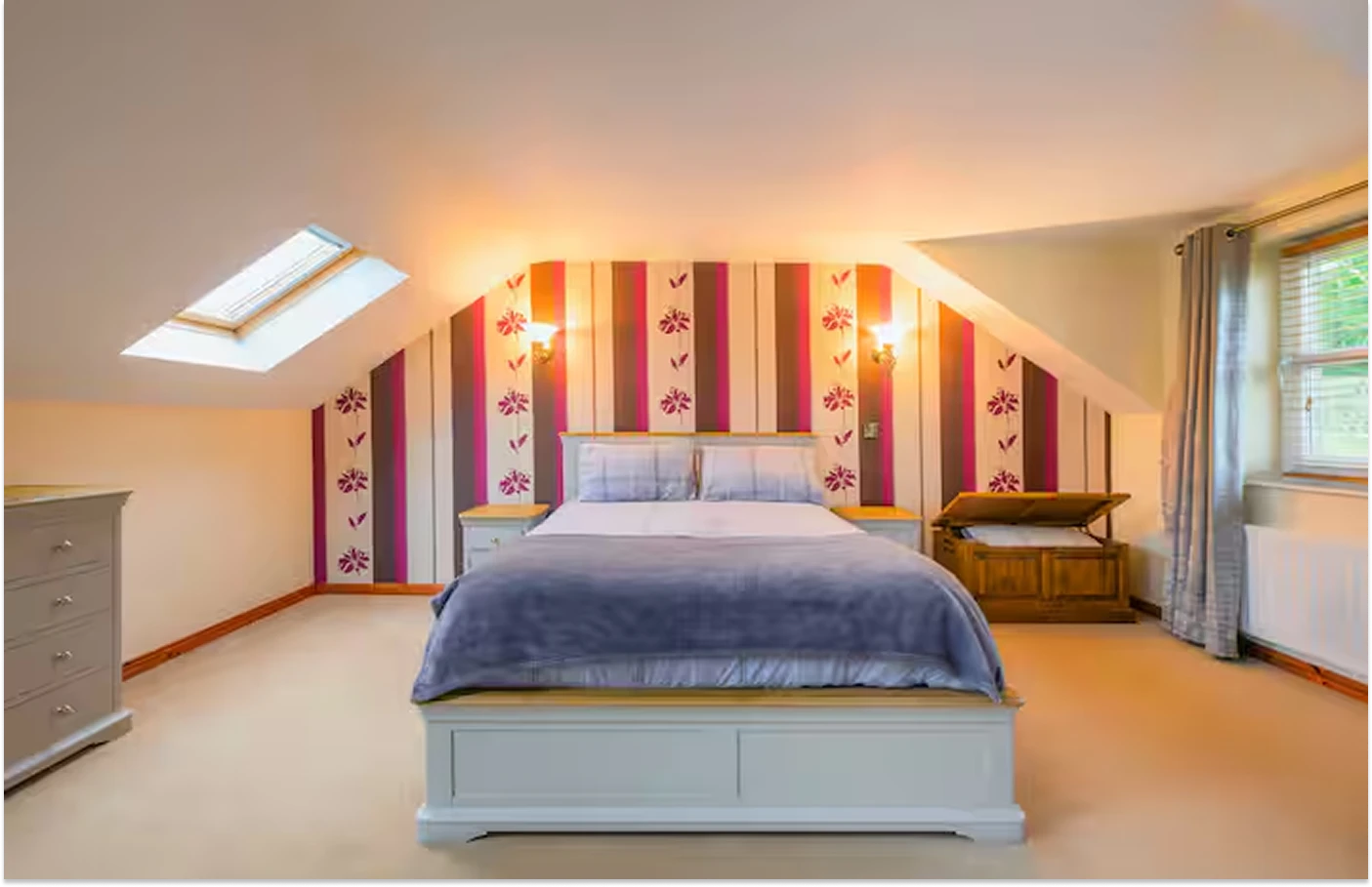 A well lit Image showcasing a bedroom at Lily's pink house with two bedside nightstands, a dresser, and chest for additional storage