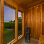 An image from inside the sauna showcasing the coals, benches, and outside view.