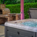 An image showcasing the hot tub on at Lily's Pink House with the brick pizza oven in the background