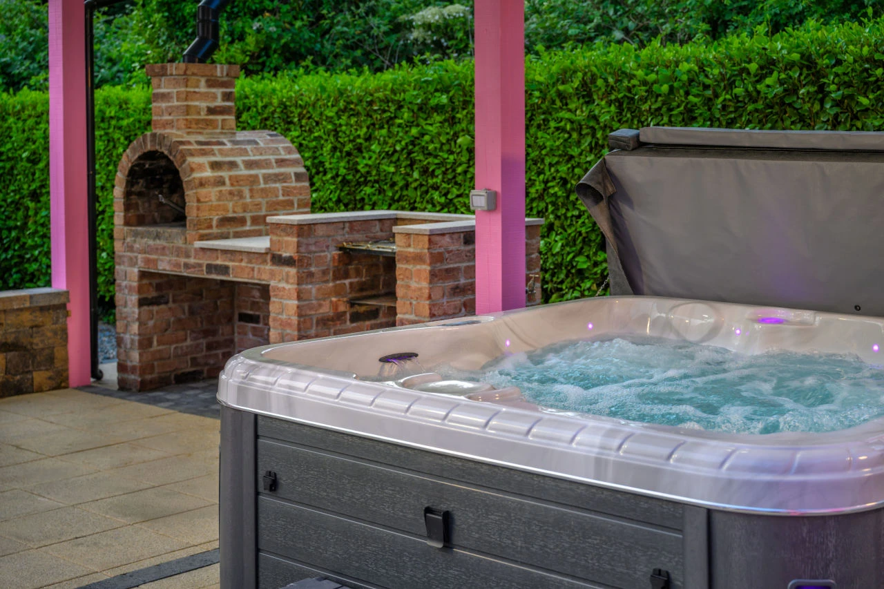 An image showcasing the hot tub on at Lily's Pink House with the brick pizza oven in the background