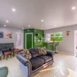 Another image of Lily's Pink house bar area with the various seating options and an open door leading to the outdoor hot tub and outdoors relaxation area.