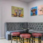 An image of some of the seating areas in Lily's Pink House showcases a padded bench with a table and some small bar stools surrounding it.