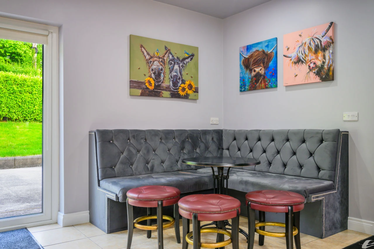An image of some of the seating areas in Lily's Pink House showcases a padded bench with a table and some small bar stools surrounding it.